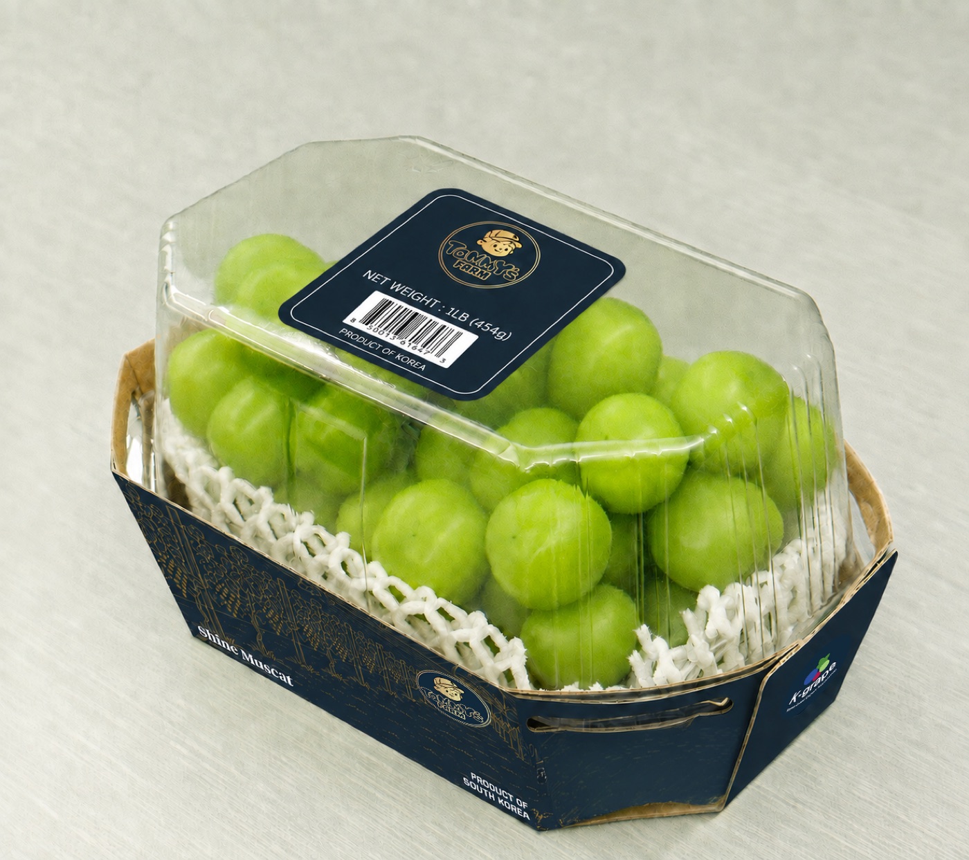 Single 1lb shine muscat clamshell in its navy tray with the Tommy's Farm label